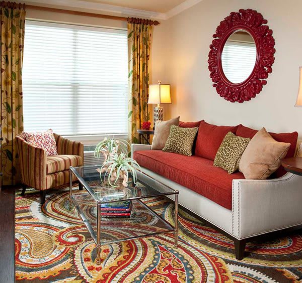A cozy living room with a colorful rug, red sofa, and patterned decor.