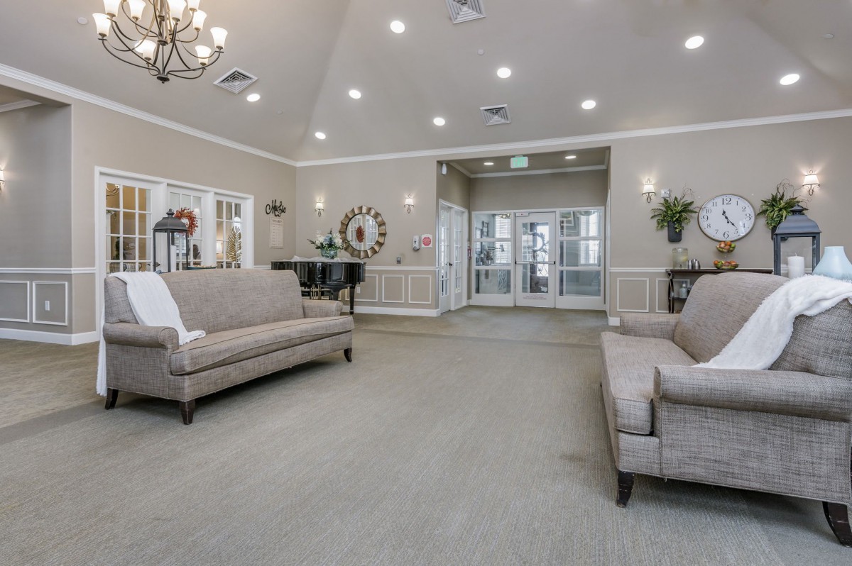 A spacious and elegantly designed living room with sofas, a chandelier, and tasteful decor.