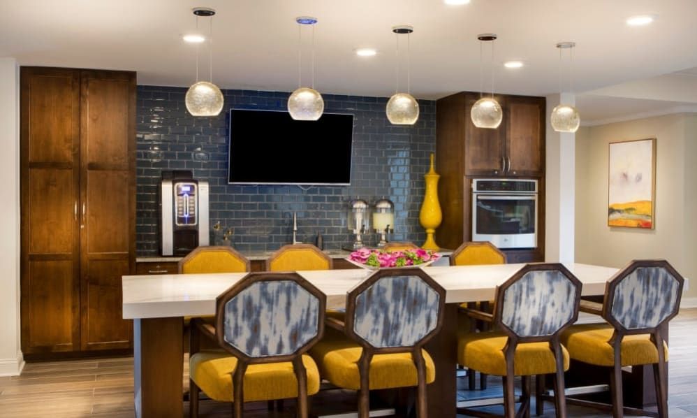 A modern kitchen with vibrant yellow seating and sleek pendant lighting.