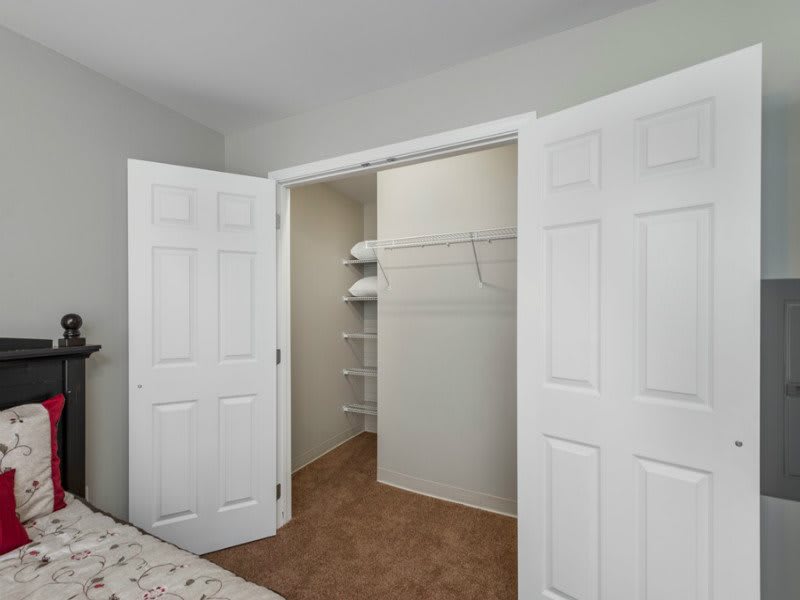 A bedroom closet with open white doors and built-in shelves.