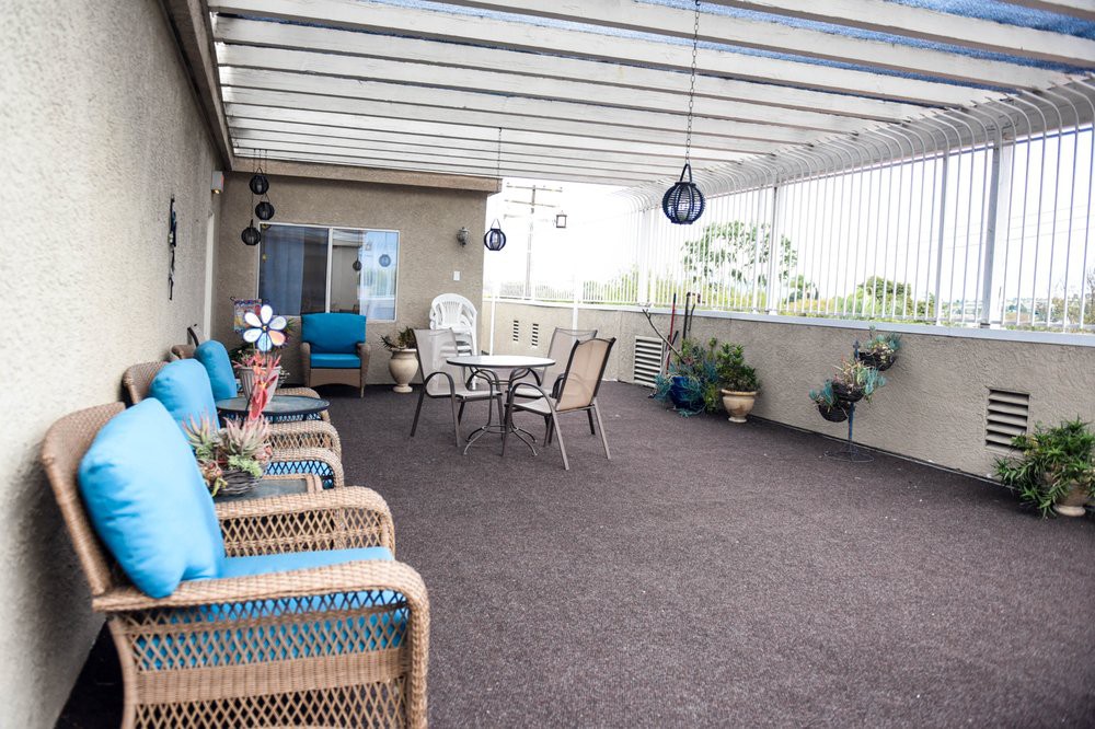 A covered patio with seating and decorative plants.