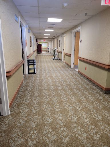 A well-lit hallway with carpeted flooring and doors along the sides.