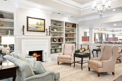 A cozy and elegantly designed living room featuring a fireplace, bookshelves filled with decor, and comfortable seating.