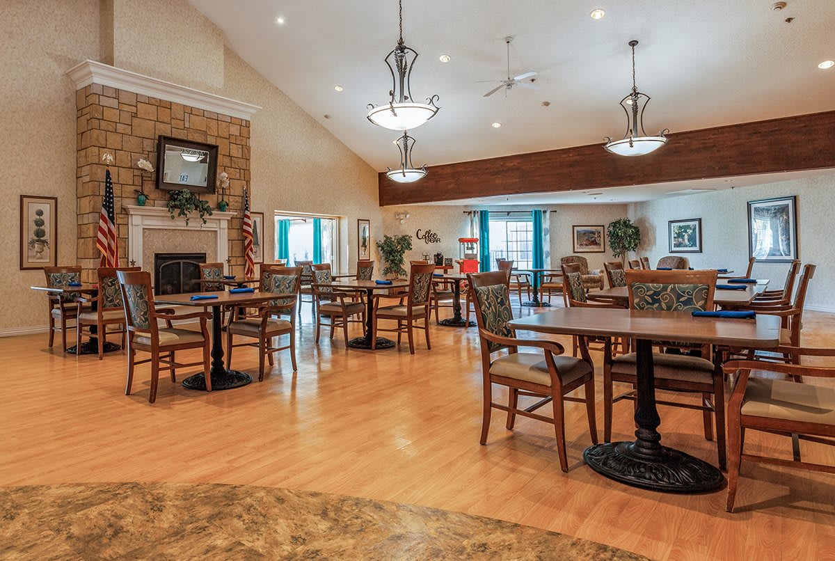 A cozy dining area with wooden tables and chairs, featuring warm lighting and a homey atmosphere.