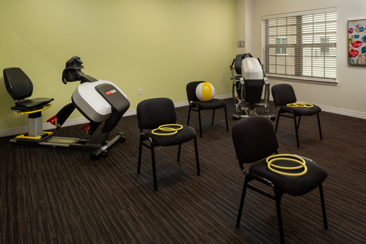 A fitness room with exercise equipment, chairs, and workout accessories prepared for a session.