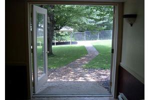 View of a backyard through an open door with a pathway leading to the garden.