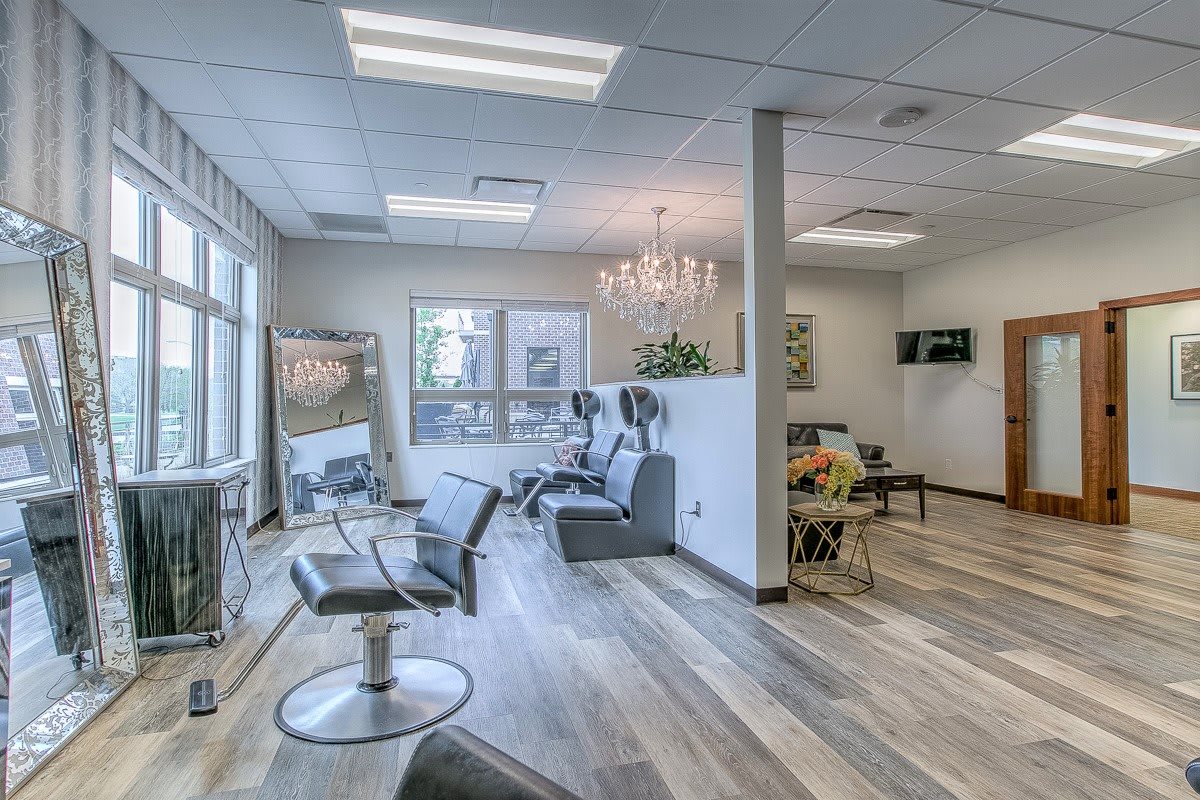 A modern and well-lit hair salon with stylish chairs and a chandelier.