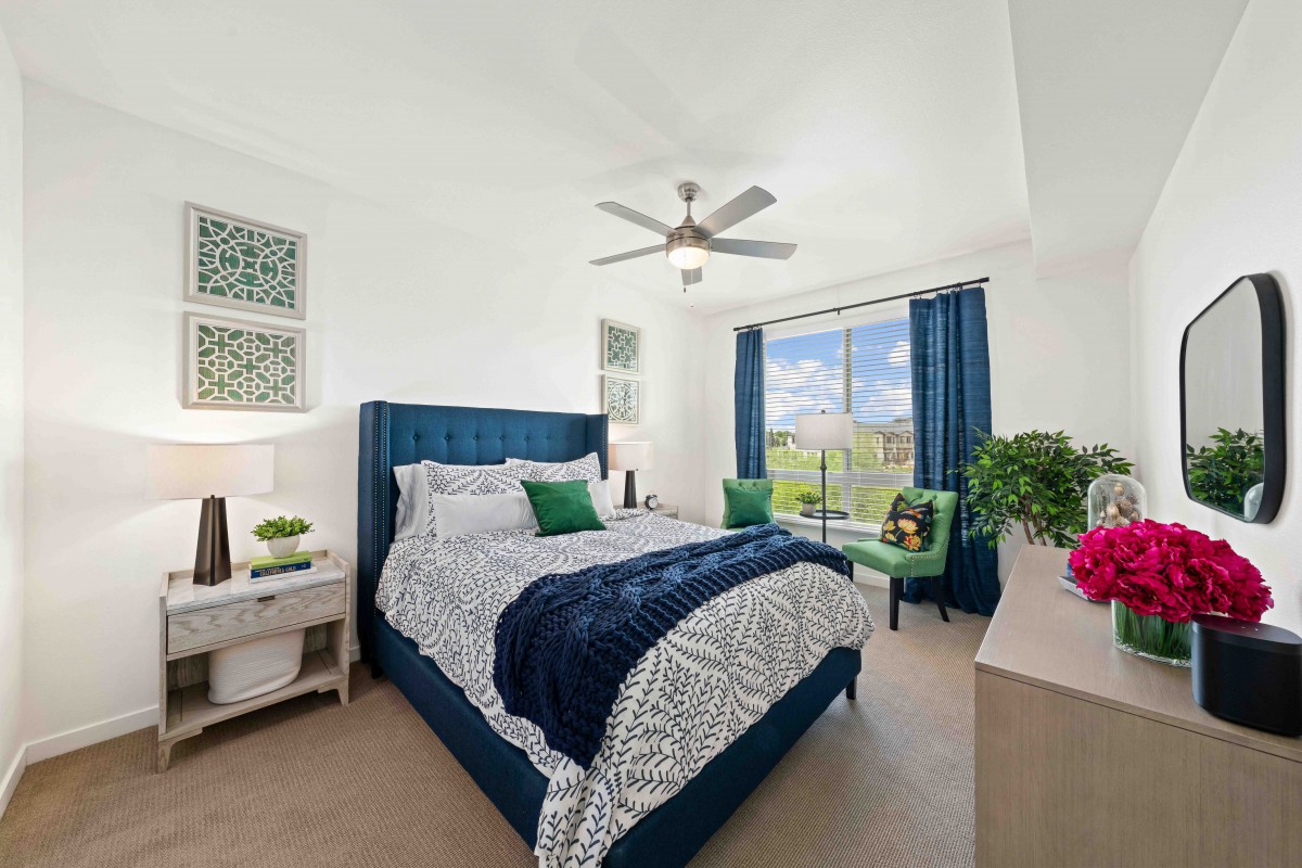 A modern bedroom with a large bed, blue and white color scheme, and a view through large windows.