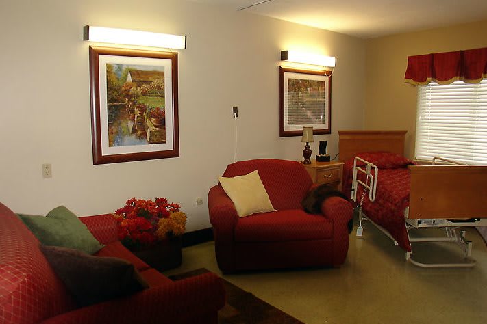 A cozy living room with red sofas, paintings on the wall, and warm lighting.