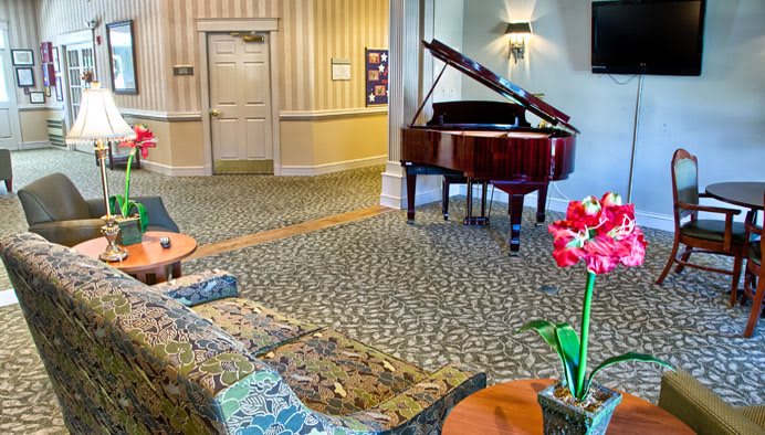 A cozy lobby featuring a grand piano and a floral arrangement.