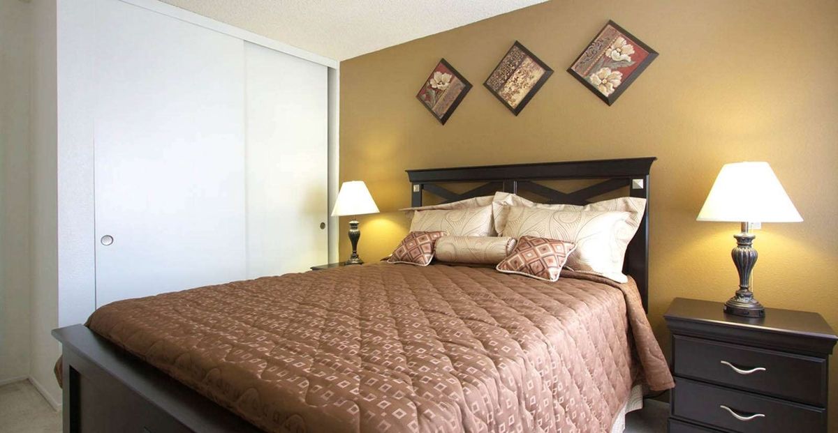A well-decorated bedroom with a large bed, pillows, and wall art.