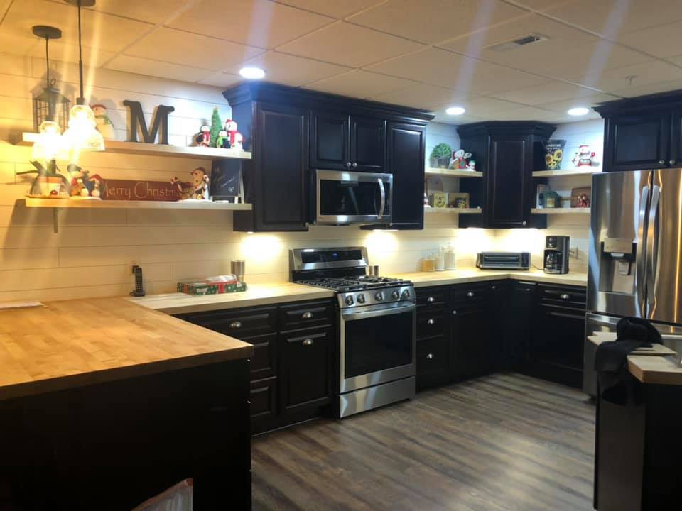 Modern kitchen with black cabinets, wooden countertops, and open shelving.