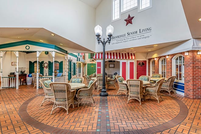 A cozy indoor seating area with wicker furniture and decorative storefronts.