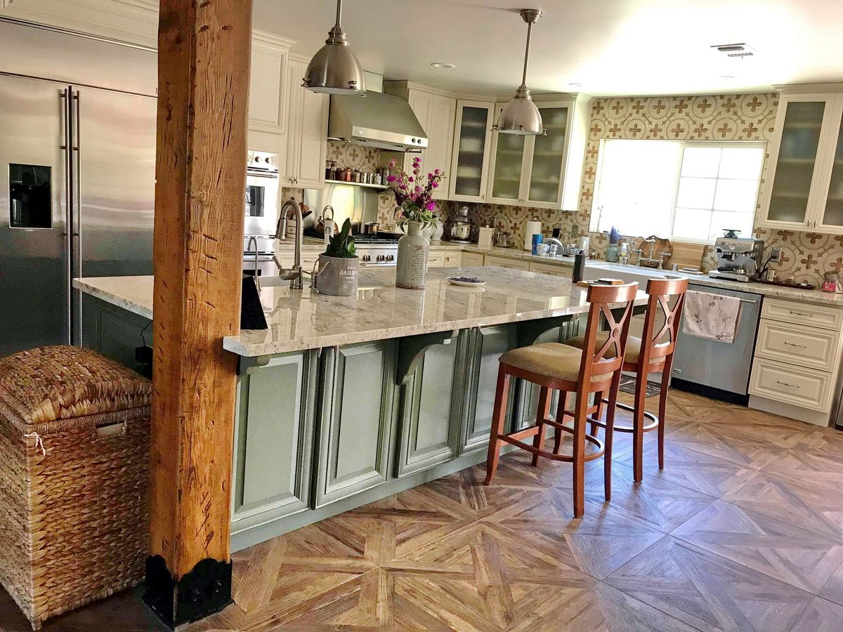 A modern kitchen with a central island, featuring bar stools and pendant lighting.