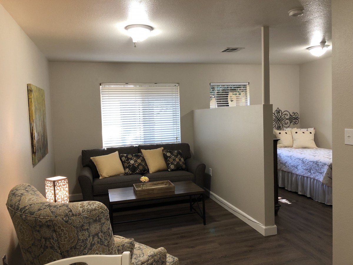 A cozy living area with a sofa and pillows adjacent to a bedroom.