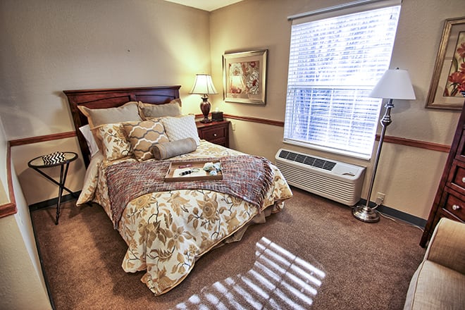 A cozy bedroom with a neatly made bed, warm lighting, and tasteful decor.
