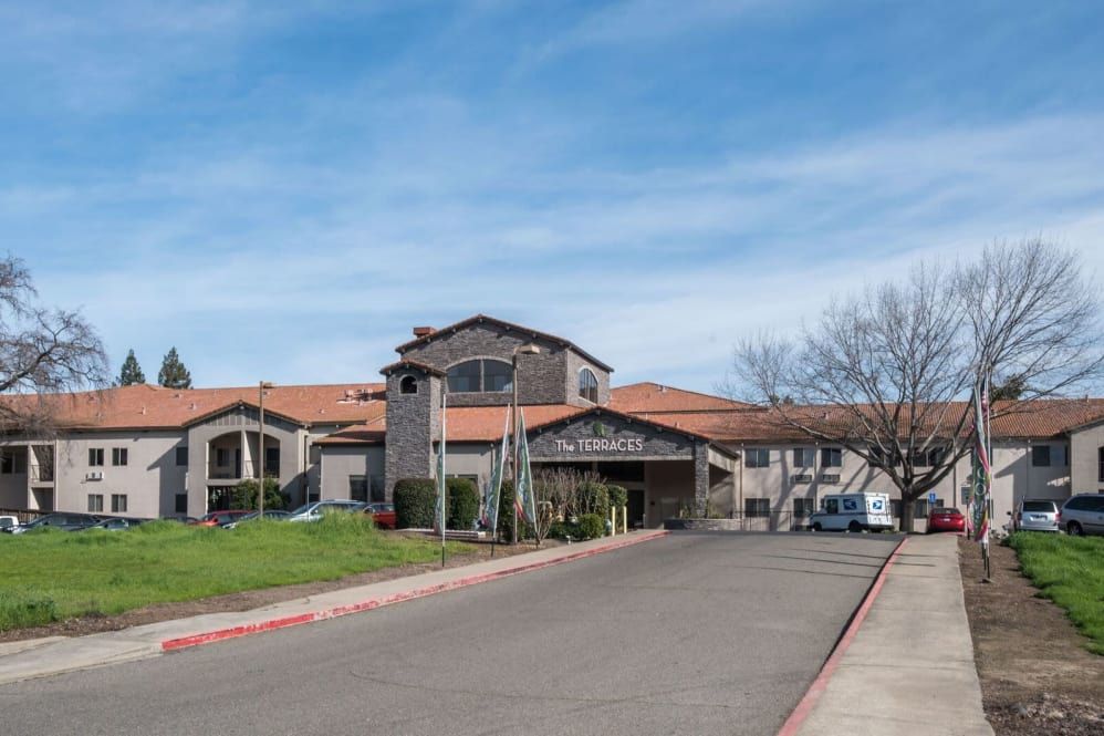 A scenic view of a large building with a driveway and clear blue sky.