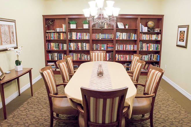 A cozy library room with a long table, surrounded by bookshelves filled with books.