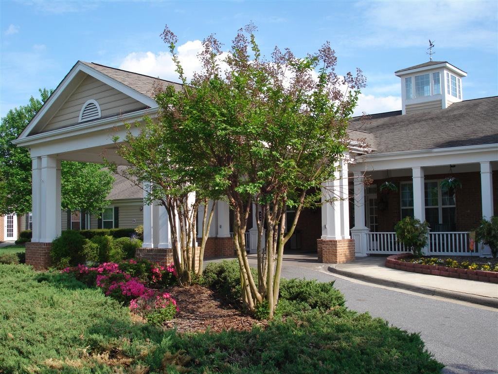 A charming building surrounded by a landscaped garden with trees and blooming flowers.