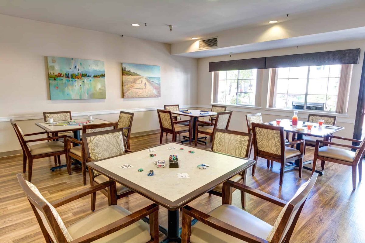 A cozy dining area with neatly arranged tables and chairs, adorned with artwork on the walls.