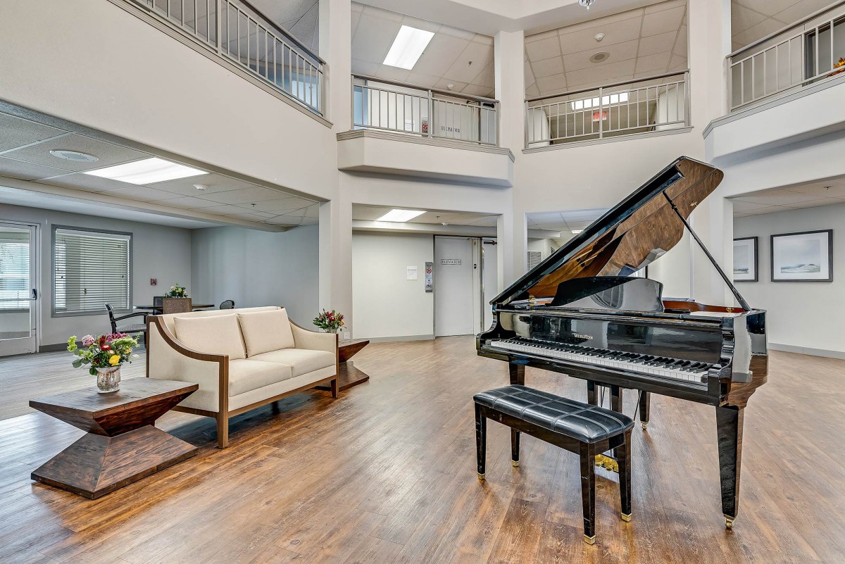 A spacious, modern lobby featuring a grand piano and comfortable seating.