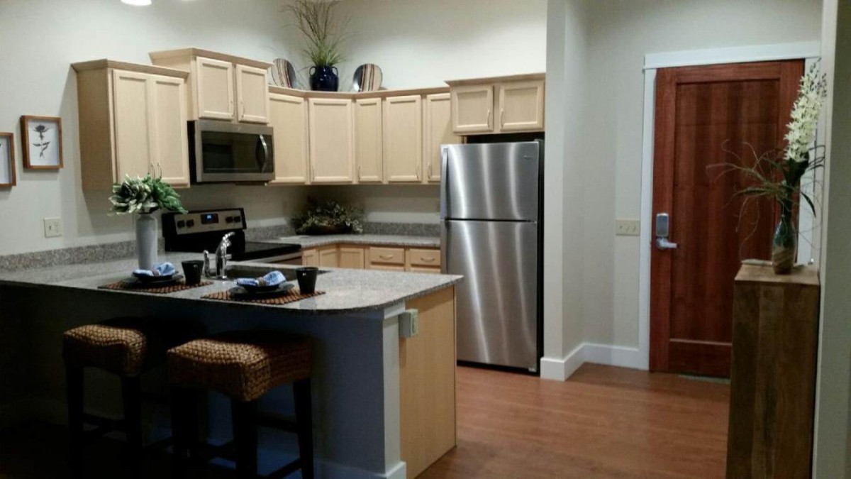 A modern kitchen with stainless steel appliances and light wood cabinets.