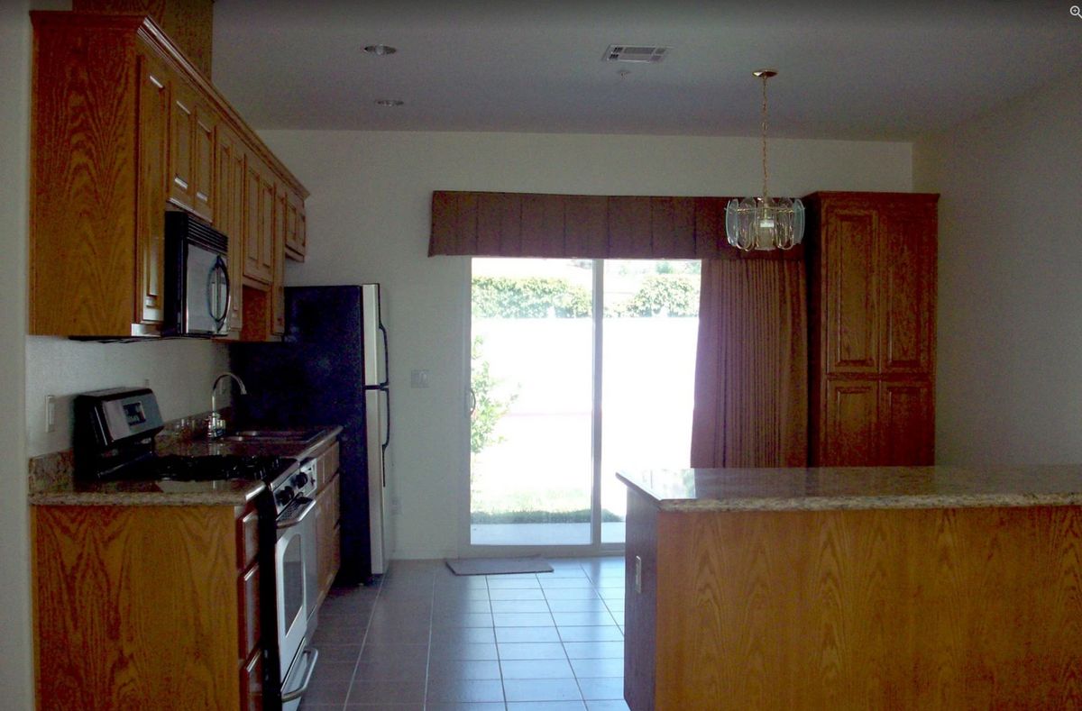 A kitchen interior featuring wooden cabinets, modern appliances, and a sliding door allowing natural light to enter.