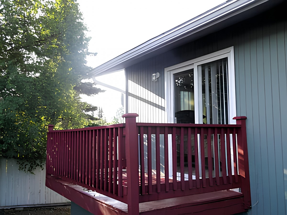 A view of a wooden deck attached to a house with sliding glass doors.