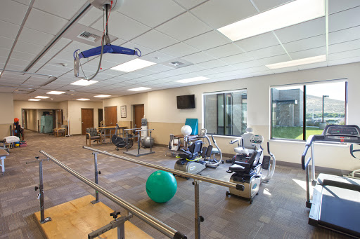 A spacious physical therapy gym equipped with various exercise machines and a blue exercise ball, designed for rehabilitation and fitness activities.