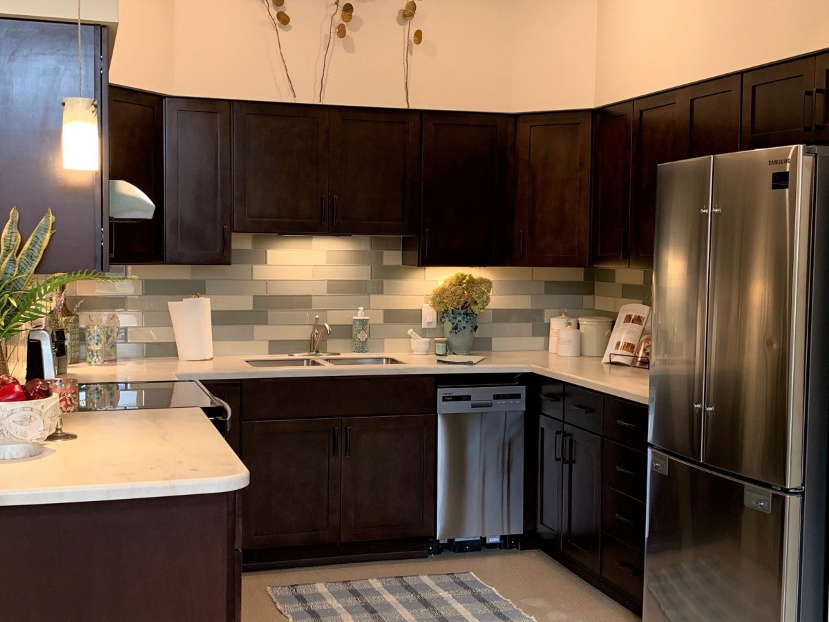 A modern kitchen featuring dark cabinets and stainless steel appliances.