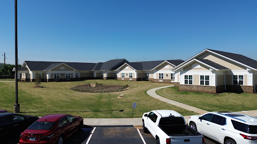 A view of residential buildings surrounded by landscaped grass and a clear blue sky.