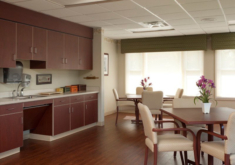 A well-lit office meeting room with tables, chairs, and cabinets.