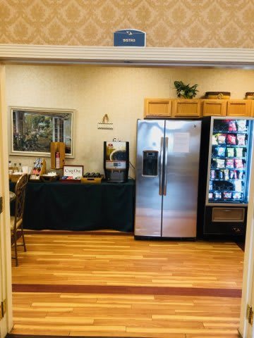 A cozy break room featuring a vending machine, a coffee station, and a refrigerator.