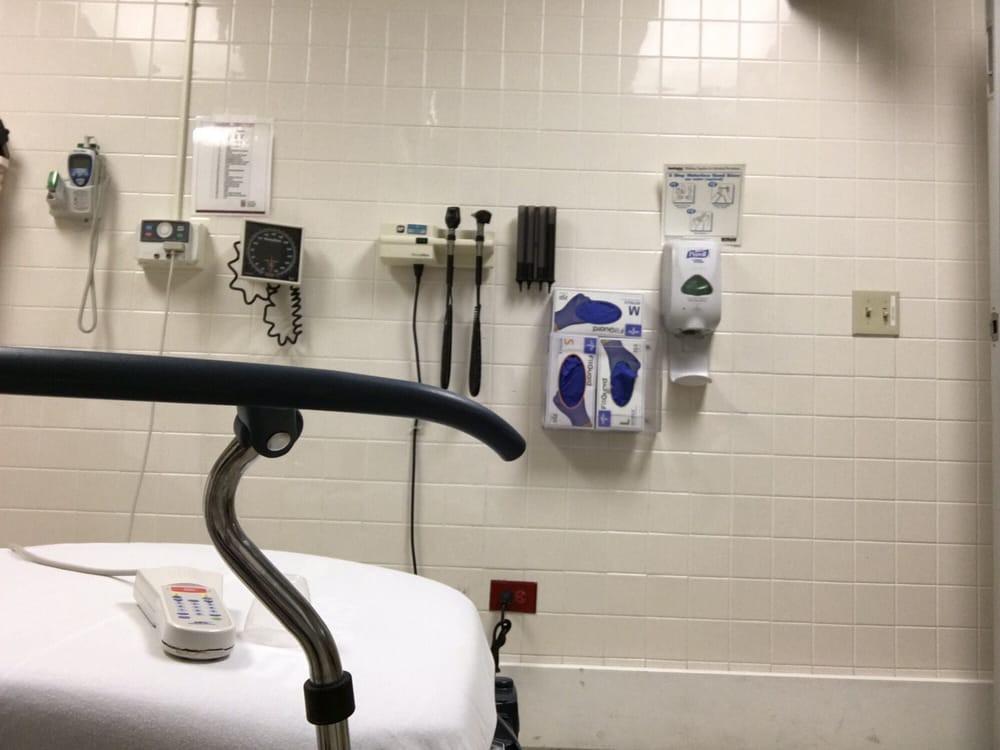 A hospital examination room featuring medical equipment and a bed.