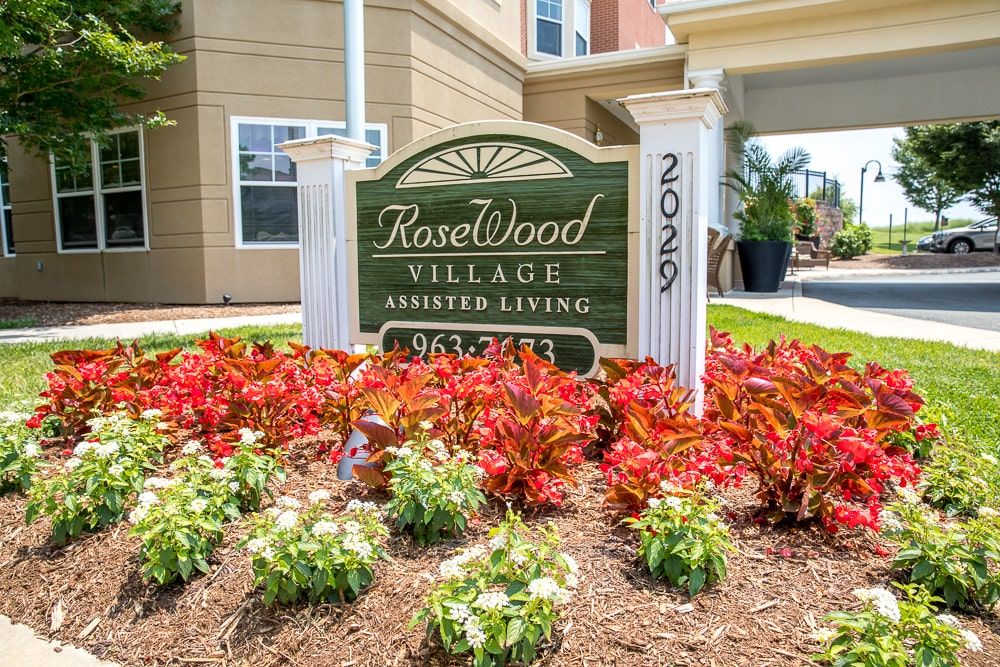 Entrance sign for Rosewood Village Assisted Living surrounded by vibrant flowers.