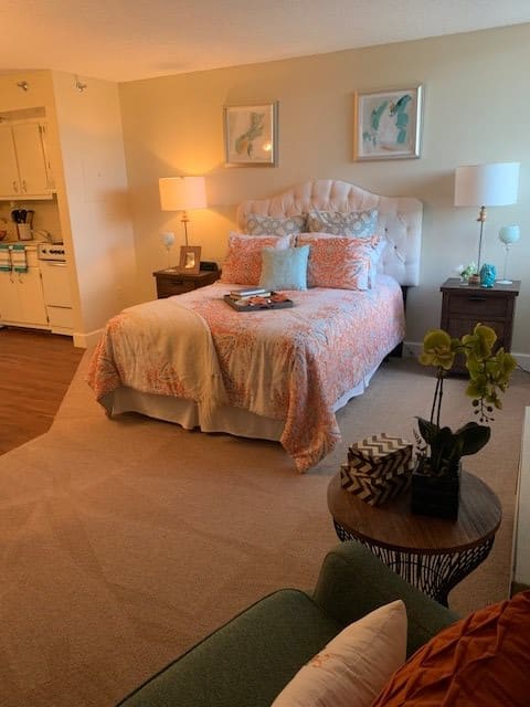 A cozy and warmly decorated bedroom with a neatly made bed, nightstands, and soft lighting.