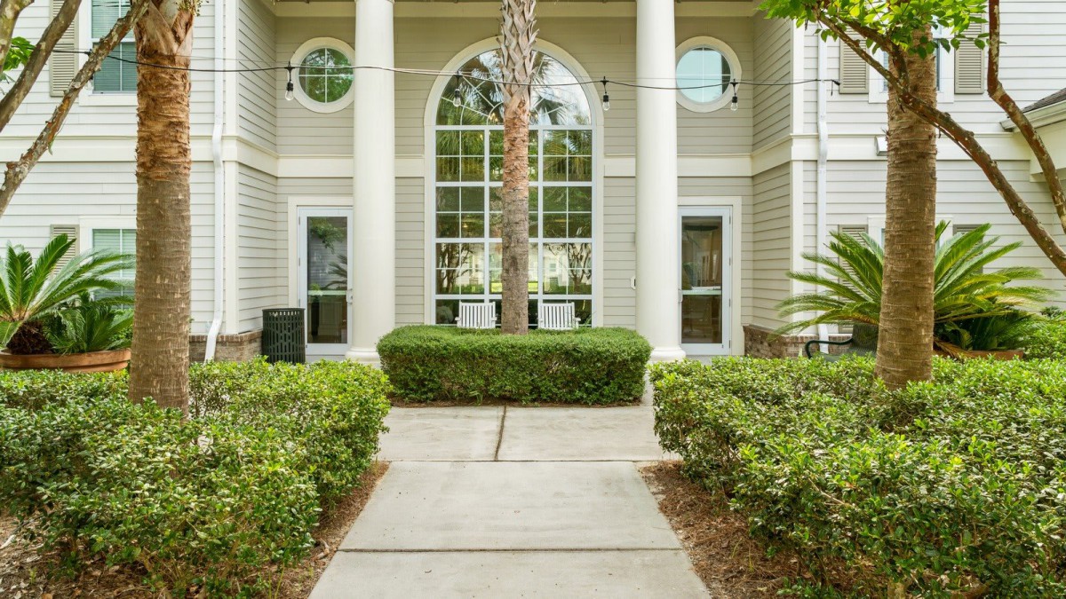 A well-maintained building entrance with large windows, columns, and manicured landscaping.