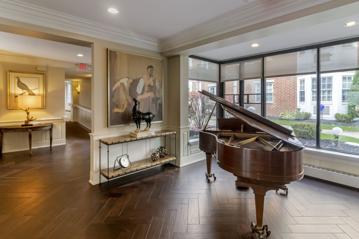 A stylish living room featuring a grand piano and elegant decor with large windows.