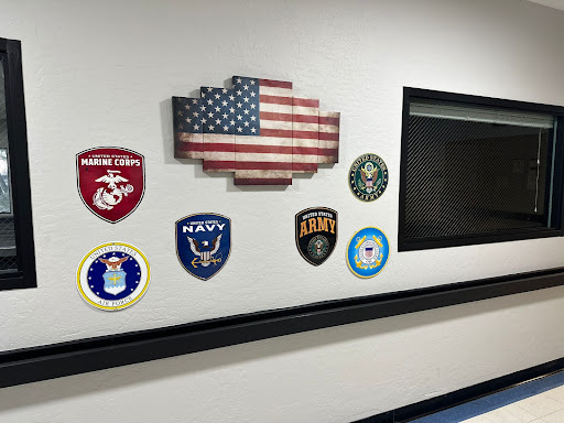 A display of military emblems and an American flag on a wall.