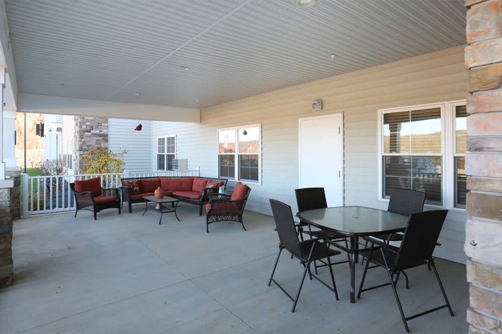A spacious outdoor patio featuring comfortable seating with a sofa and chairs, under a covered area.