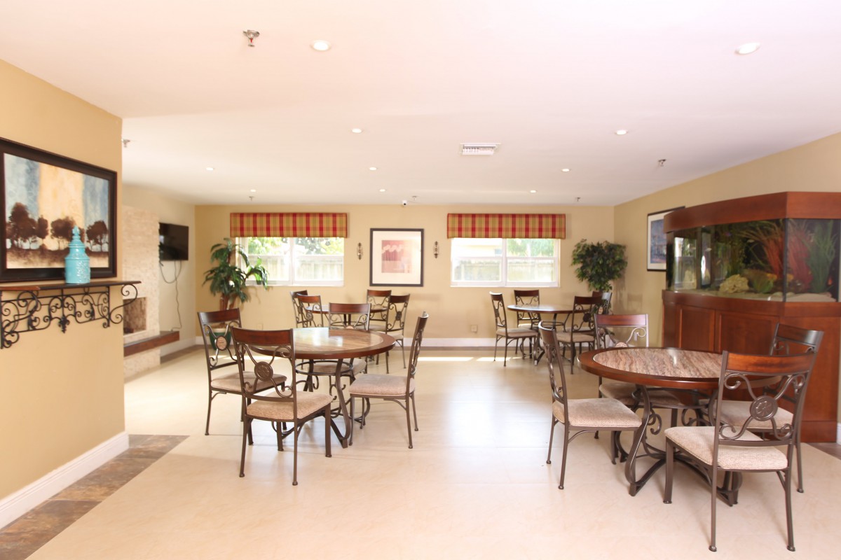 A well-lit dining area with multiple tables and chairs, featuring modern decor and large windows.