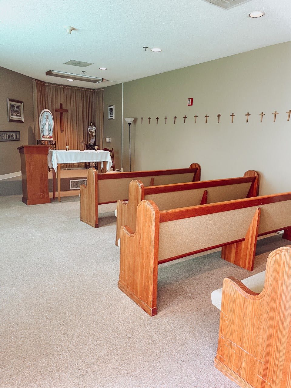 A small chapel with wooden pews and an altar, designed for quiet prayer and reflection.