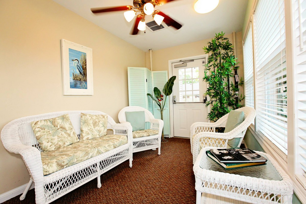 A cozy living room featuring wicker furniture and indoor plants.