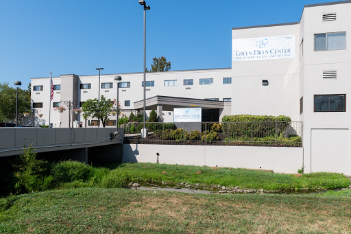 A modern healthcare facility surrounded by greenery under a clear blue sky.