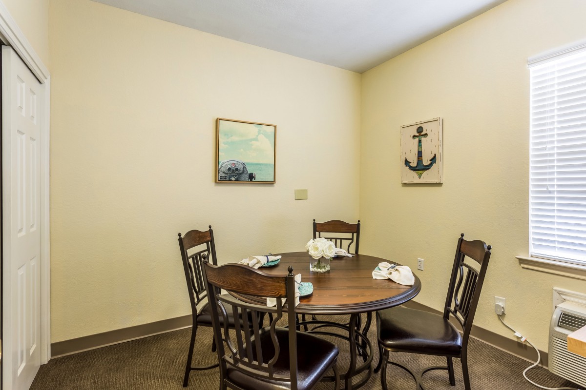 A cozy dining area featuring a round table with four chairs and nautical-themed wall decor.