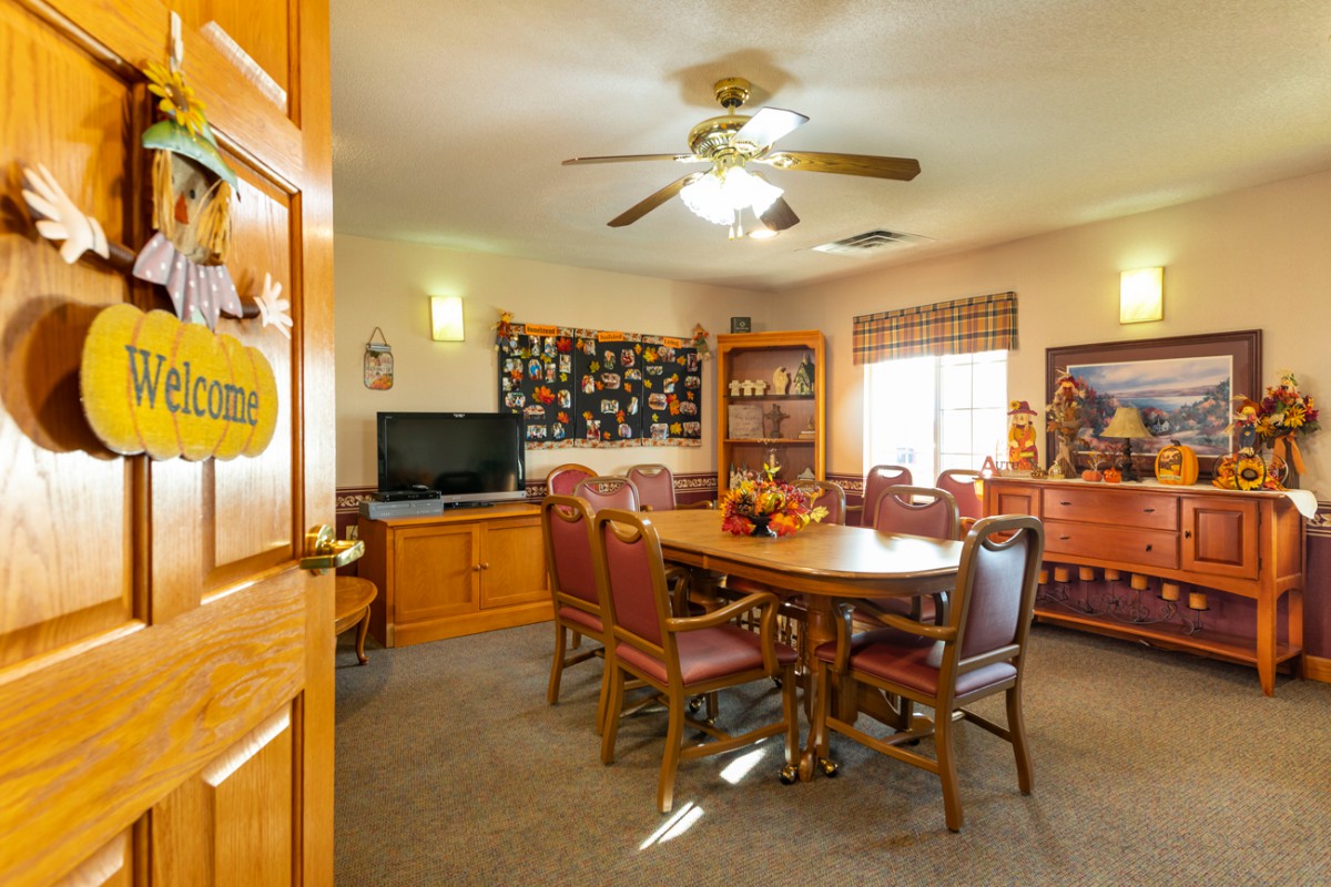 A cozy dining room featuring a wooden table with chairs, a television, and decorative elements on the walls.