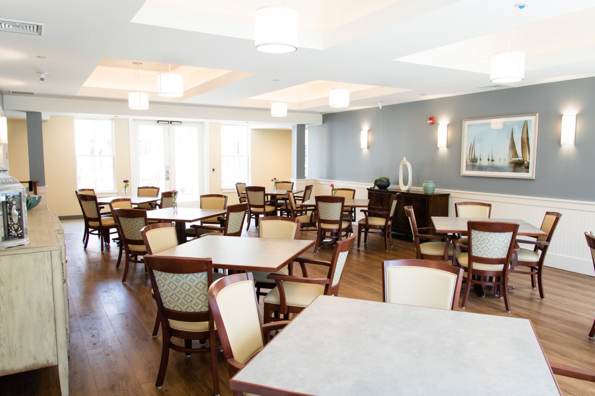 A modern dining room with neatly arranged tables and chairs, featuring elegant lighting.