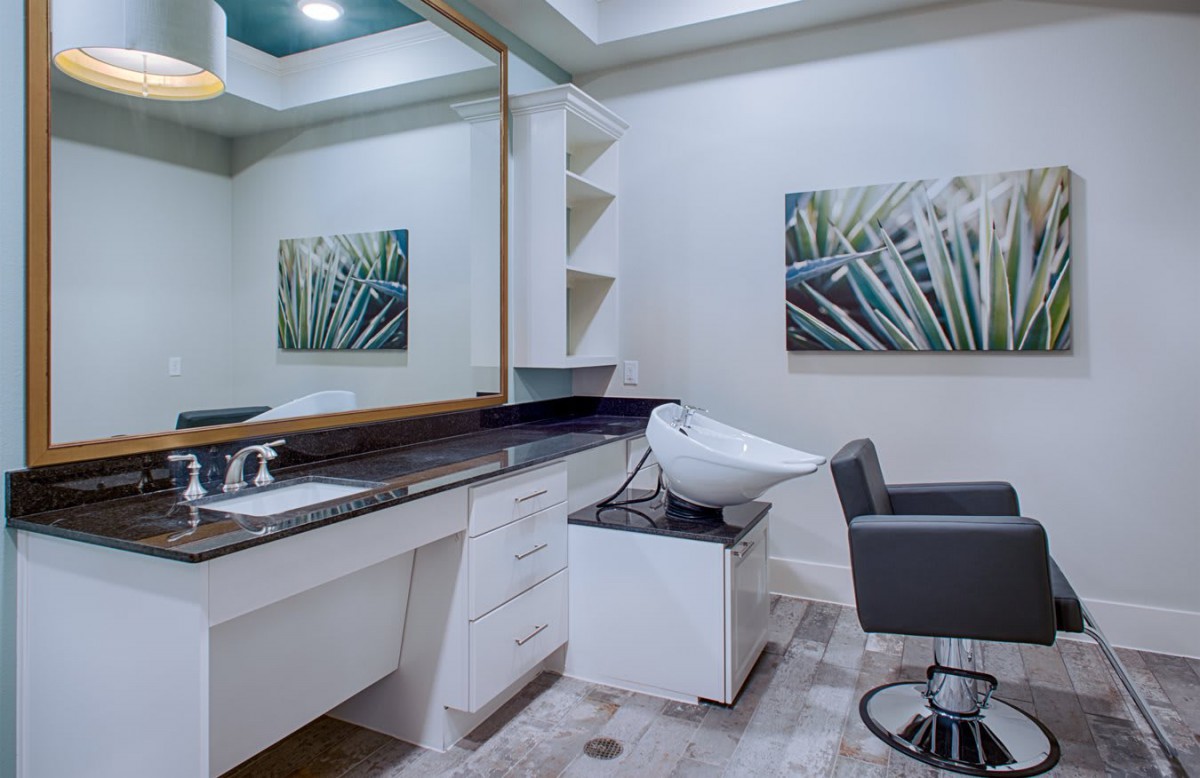 A modern hair salon interior with a sink, mirror, and styling chair.