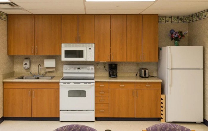 A kitchen with wooden cabinets, featuring a stove, microwave, coffee maker, and toaster.