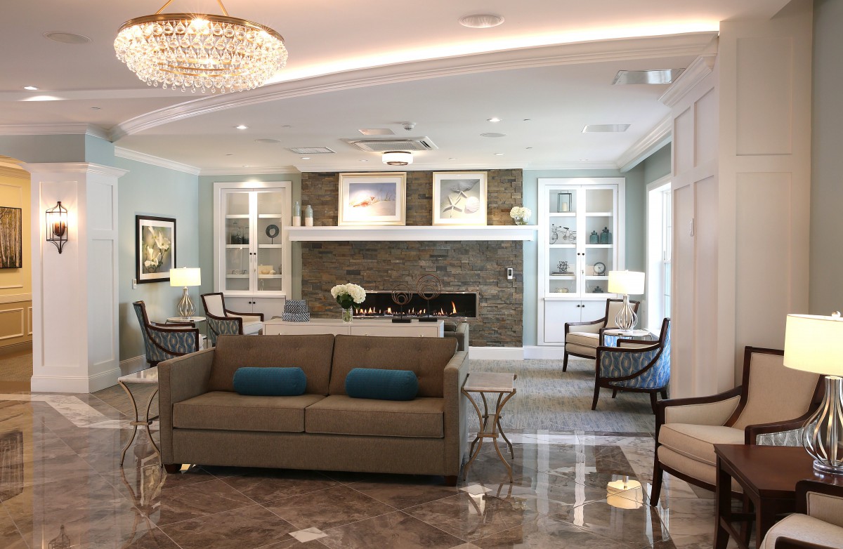 A modern and cozy living room featuring a comfortable sofa, elegant fireplace, and stylish chandelier.